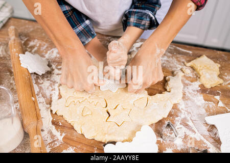 Mains de la mère et le fils de cookies coupe pâte roulée pendant la cuisson de la pâtisserie pour le dîner de Noël Banque D'Images
