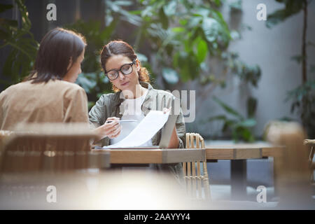 Portrait de deux femmes chefs de projet de discuter tout en travaillant à table dans une terrasse de café, copy space Banque D'Images