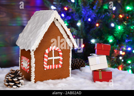 La mangeable gingerbread house, neige, cadeaux et décoration Nouvel An des arbres avec guirlande en arrière-plan Banque D'Images