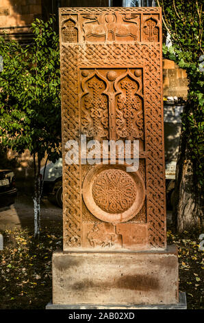 Khatchkar rouge avec animaux stylisés, deux arches avec des croisements, la figure d'un Saint sur un cheval, un symbole de l'éternité sur l'allée de croix en pierre en G Banque D'Images