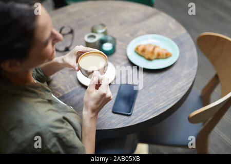 Portrait of smiling young woman holding cup de café latte sur table en bois en français cafe, copy space Banque D'Images