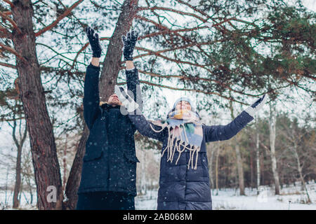 Activités d'hiver. Couple throwing snow en hiver forêt. Les gens se détendre et s'amuser en plein air Banque D'Images