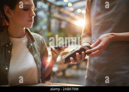 Portrait Portrait de jeune femme de payer via NFC dans un café, se concentrer sur les mains tenant terminal bancaire, copy space Banque D'Images