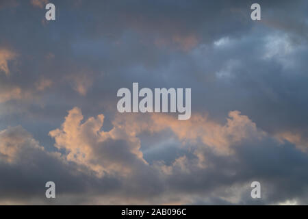 Maquereaux ciel. Ciel bleu avec nuages fragmentés de lumière avec le soleil donnant une douce couleur rose / orange Banque D'Images