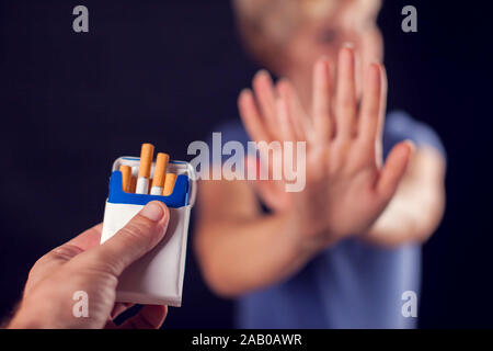 La femme en bleu t-shirt refusant des cigarettes sur fond noir. Concept d'arrêter de fumer Banque D'Images