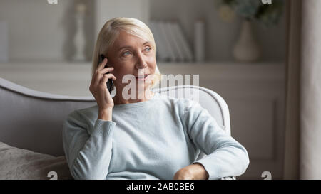 60 femme siéger sur la table pour maintenir le téléphone à discuter avec tes amis Banque D'Images