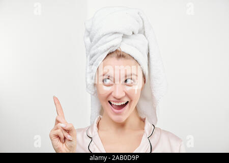 Heureux belle femme avec sous-eye patches sur le visage et towel on head Banque D'Images