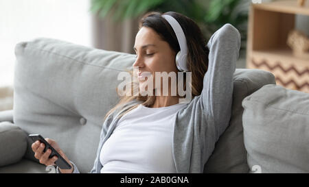 Femme portant un casque sans fil musique écoute assis relaxant sur table Banque D'Images