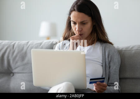 Concerné woman holding au tour ordinateur dans la main une carte de crédit Banque D'Images