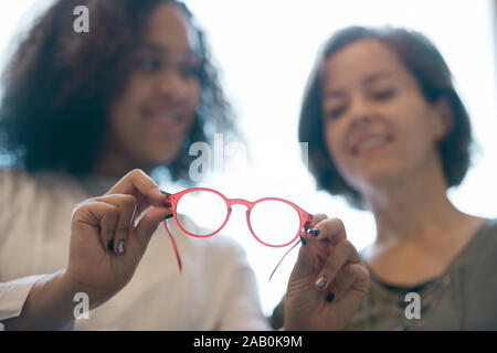 Paire de lunettes dans les mains de jeunes cliniciens-optique lors de la consultation Banque D'Images