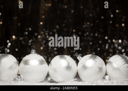 Décorations de Noël sur la composition de cinq d'argent soir avec des boules de neige blanche sur elle sur fond sombre avec des couleurs argent et or bokeh. Holida Banque D'Images