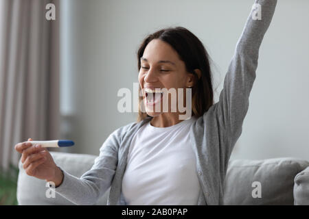 Test de grossesse utilisation femme voir deux rayures célébrant se sent heureux Banque D'Images