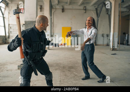 L'homme militaire avec ax, zombie en usine abandonnée Banque D'Images