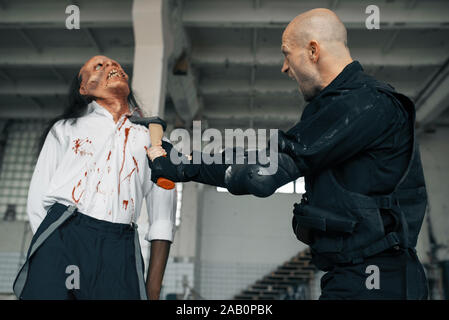 L'homme militaire avec ax, zombie en usine abandonnée Banque D'Images
