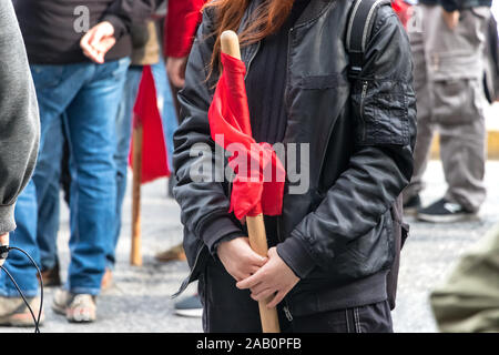 Parti communiste KKE supportrice tenant son drapeaux rouges debout à côté du bâtiment de l'Université Polytechnio. Banque D'Images