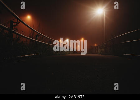 Lumière dramatique sur un pont pendant une nuit brumeuse à Leipzig, Allemagne Banque D'Images