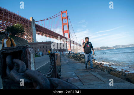 Un homme s'entretient au téléphone tout en marchant près de Fort Point à San Francisco. Banque D'Images