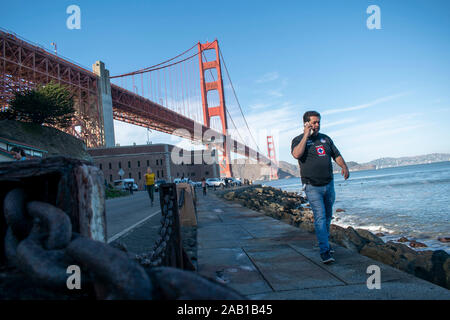 Un homme s'entretient au téléphone tout en marchant près de Fort Point à San Francisco. Banque D'Images