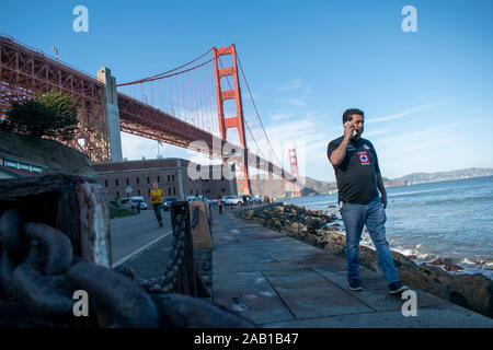 Un homme s'entretient au téléphone tout en marchant près de Fort Point à San Francisco. Banque D'Images