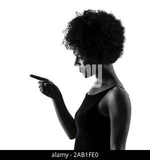 Un jeune adolescent africains mixed race girl woman pointing silhouette ombre en studio isolé sur fond blanc Banque D'Images