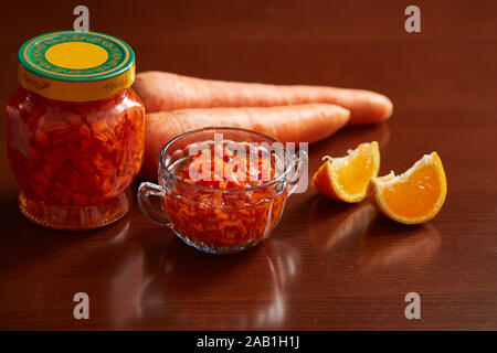 Dans un pot de confiture de carotte et le bol, les carottes, le mandarin de tranches pour décoration sur une table en bois sombre. Banque D'Images