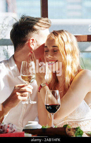 Laughting Happy young woman listening to ami chuchotant ses compliments et mots romantique Banque D'Images