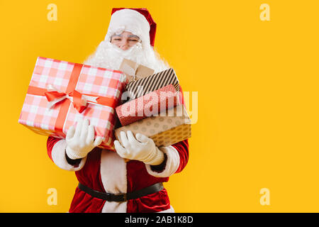 Heureux satisfait le Père Noël avec les mains pleines de cadeaux Banque D'Images