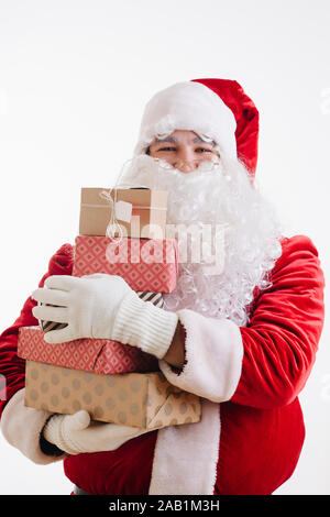 Sourire joyeux Père Noël avec les mains pleines de cadeaux pour Noël Banque D'Images