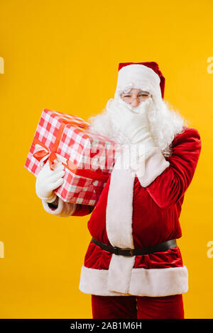 Heureux le Père Noël avec un présent dans la main caressant sa barbe. Banque D'Images