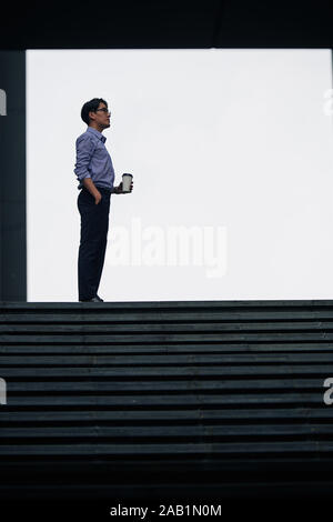 Businessman with tourné vers le haut de chemise bénéficiant d'Pause café après une longue journée de travail Banque D'Images