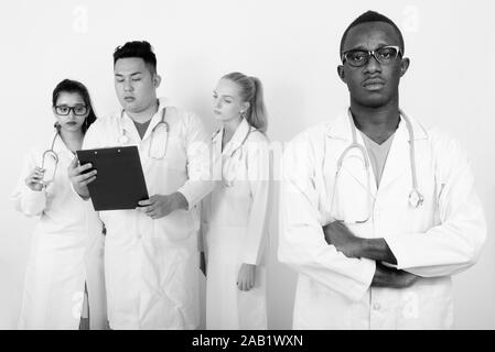 Portrait de jeune homme africain médecin avec les bras croisés et divers groupes ethniques de la lecture sur l'ensemble des médecins du presse-papiers Banque D'Images