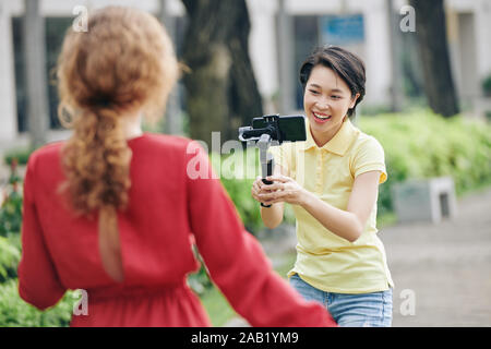 Laughing woman with smartphone connecté à monopod aidant à faire blogger femelle vidéo amusante Banque D'Images