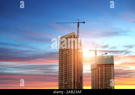 Site de construction, des silhouettes d'ouvriers de l'industrie de la construction sur des échafaudages contre la lumière au coucher du soleil. Banque D'Images