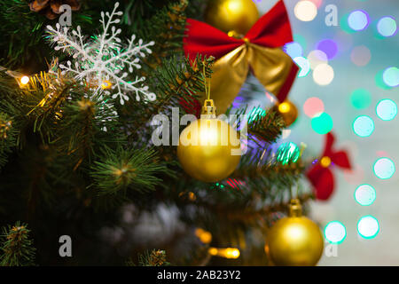 Beau vert sapin de Noël décoré avec des boules jaunes, rouges des arcs et des guirlandes. Photo en gros plan. Fond mousseux Banque D'Images
