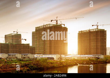 Site de construction, des silhouettes d'ouvriers de l'industrie de la construction sur des échafaudages contre la lumière au coucher du soleil. Banque D'Images