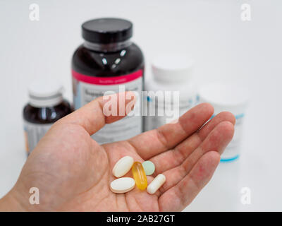 Assorted pills sur ouvrez Palm sur avec bouteilles de pilules dans l'arrière-plan. Trop de comprimés / médicament / Suppléments alimentaires / concept vitamines Banque D'Images