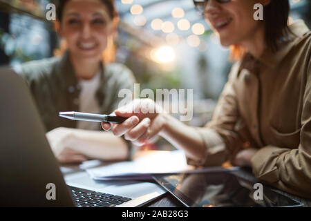 Portrait de jeune femme moderne pointant sur l'écran du portable lors de réunion d'affaires à café avec tes collègues de sexe féminin, copy space Banque D'Images