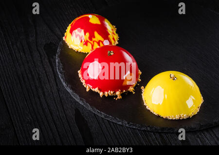 Beaux gâteaux couverts de glaçage jaune et rouge brillant. Concept design desserts pâtisserie Banque D'Images