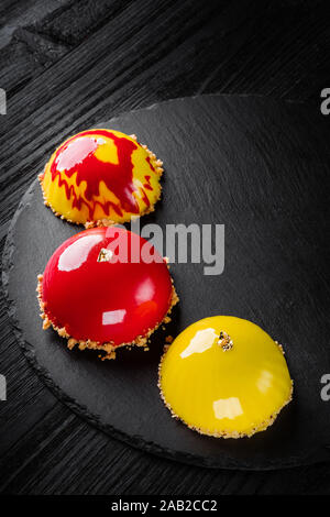 Beaux gâteaux couverts de glaçage jaune et rouge brillant. Concept design desserts pâtisserie Banque D'Images