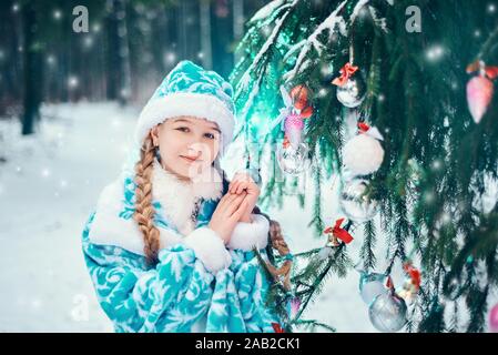 Petite fille décore un arbre de Noël dans la forêt Banque D'Images