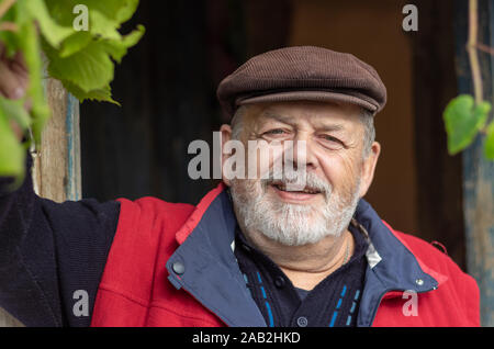 Beau portrait positif de barbu paysan ukrainien senior contre vieille grange entrée Banque D'Images