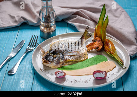 La friture de poissons dorado, décoré avec des concombres et oignons. Sur un fond de bois bleu Banque D'Images