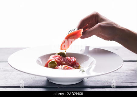 Close-up délicieux tartare de thon sur une plaque blanche sur l'original recette italienne avec de l'huile d'olive, les épices et le jus de lime. Recette de cuisine méditerranéenne Banque D'Images