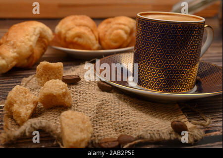 Tasse à café, sucre brun, croissants, les grains de café sur fond de bois. Close up Banque D'Images