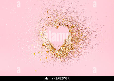 Forme de coeur fait de paillettes et d'étoiles dorées sur fond rose. Valentines Day, love concept. Banque D'Images