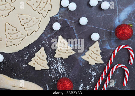 Passage télévision lay concept pour la cuisson de cookies de Noël avec déployé, pâte à biscuits, cookies en forme d'arbres de Noël, des cannes de bonbon et red tree Banque D'Images
