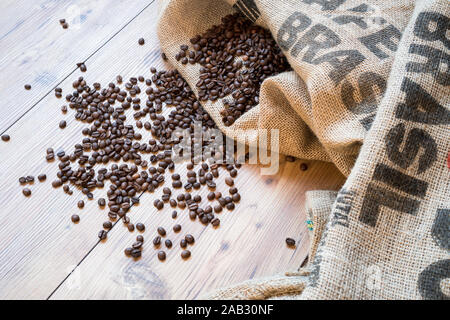 Les grains de café sur le sac de jute et imprimé Brasil sur plancher en bois. Sac de café Banque D'Images