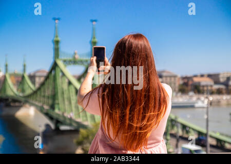 Belle jeune fille rousse dans une robe d'été otton prend des photos du pont historique Banque D'Images