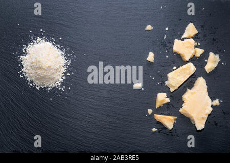 Vue de dessus de savoureux morceaux frais et fromage parmigiano râpé sur fond d'ardoise noire Banque D'Images