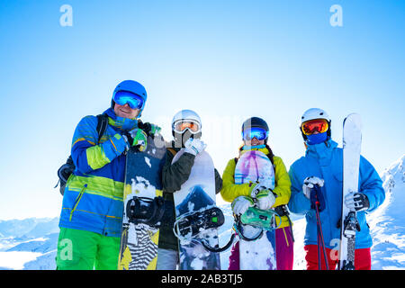 Quatre athlètes heureux en casque et avec les planches dans leurs mains à snow resort sur journée d'hiver Banque D'Images